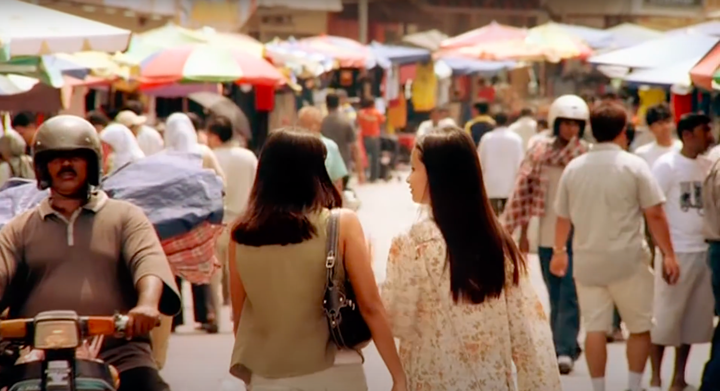 The backs of two teenage girls as they walk through a busy market