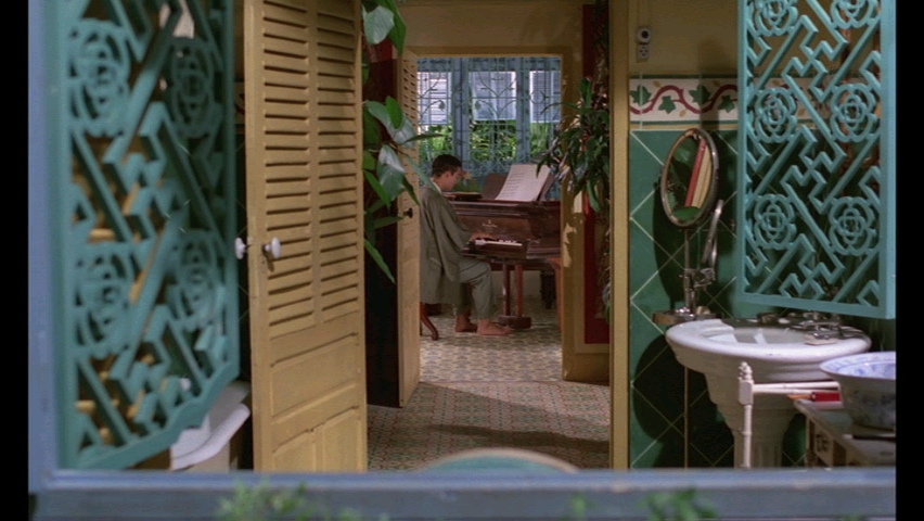 A scene through a window of a man playing piano